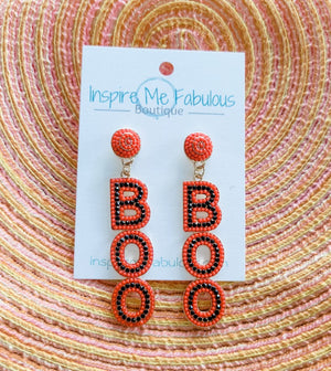A pair of beaded earrings designed with the word 'BOO' in orange and black colors, displayed on a cardboard holder with the brand 'Inspire Me Fabulous Boutique'.