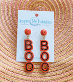 A pair of beaded earrings designed with the word 'BOO' in orange and black colors, displayed on a cardboard holder with the brand 'Inspire Me Fabulous Boutique'.