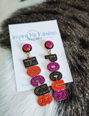 Colorful earrings on a card with 'Inspire Me Fabulous' branding, placed on a fur surface.