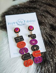 Colorful earrings on a card with 'Inspire Me Fabulous' branding, placed on a fur surface.