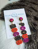 Colorful earrings on a card with 'Inspire Me Fabulous' branding, placed on a fur surface.